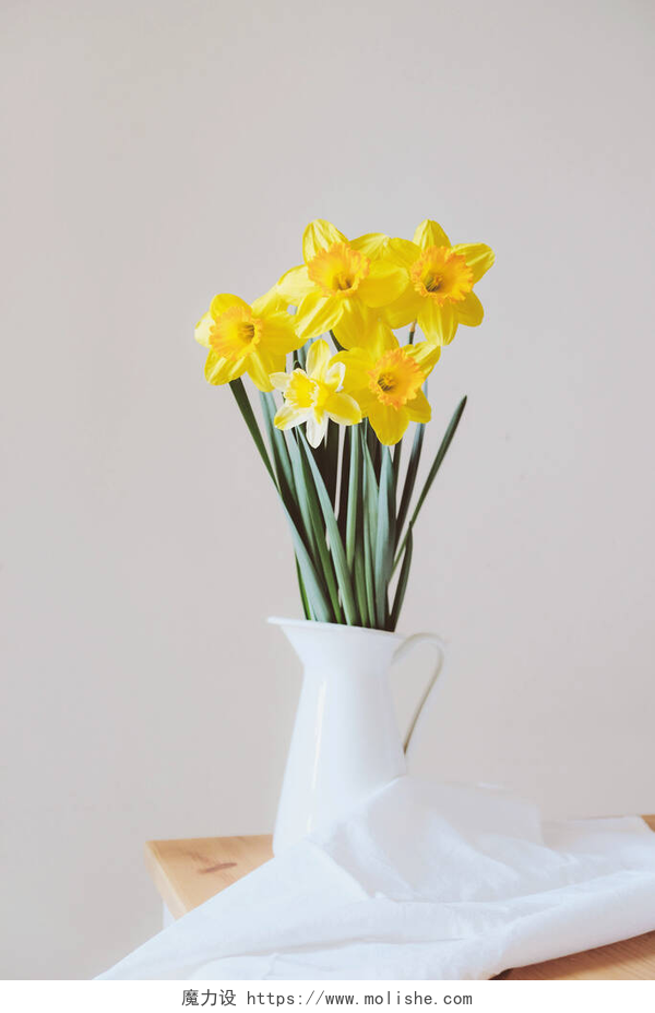 花瓶里的水仙花美丽的一束淡黄色的水仙花，盛开在花瓶里，衬托着白色的背景，闭合在一起。文字空间。春天的花朵。母亲节卡片。沉默寡言的生活.